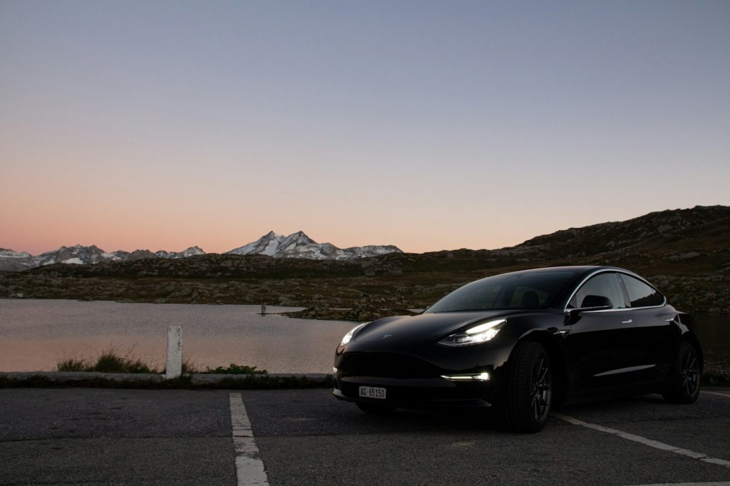 Tesla Model 3 negro junto a un lago al atardecer